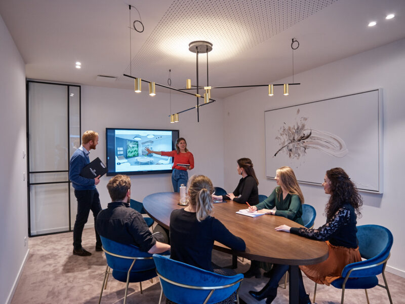 Architecten van Architime zitten rond te tafel en kijken naar smartboard.
